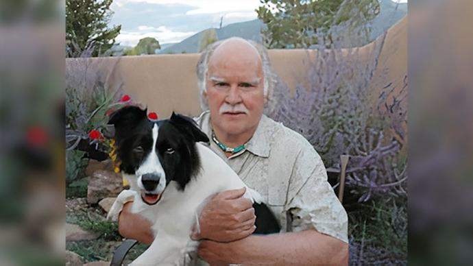 拉里·金梅尔抱着他的狗，新墨西哥州的背景