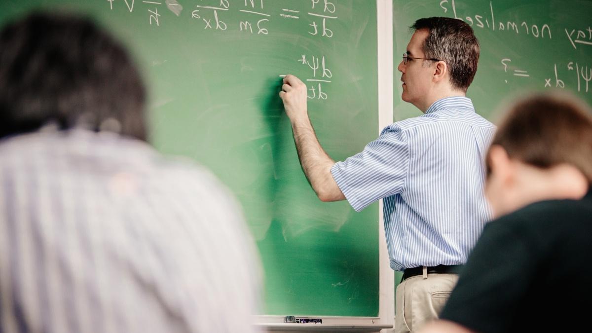 教授 at the chalkboard writing out equations