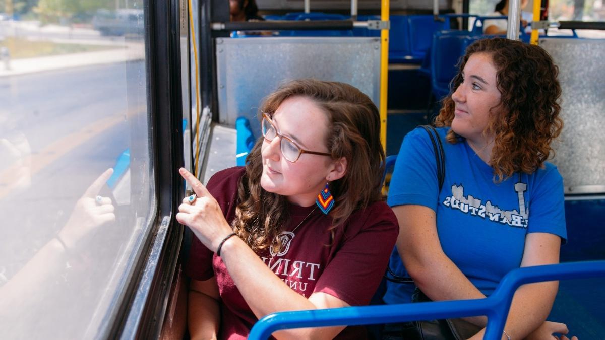 两个学生坐在公交车上看着窗外