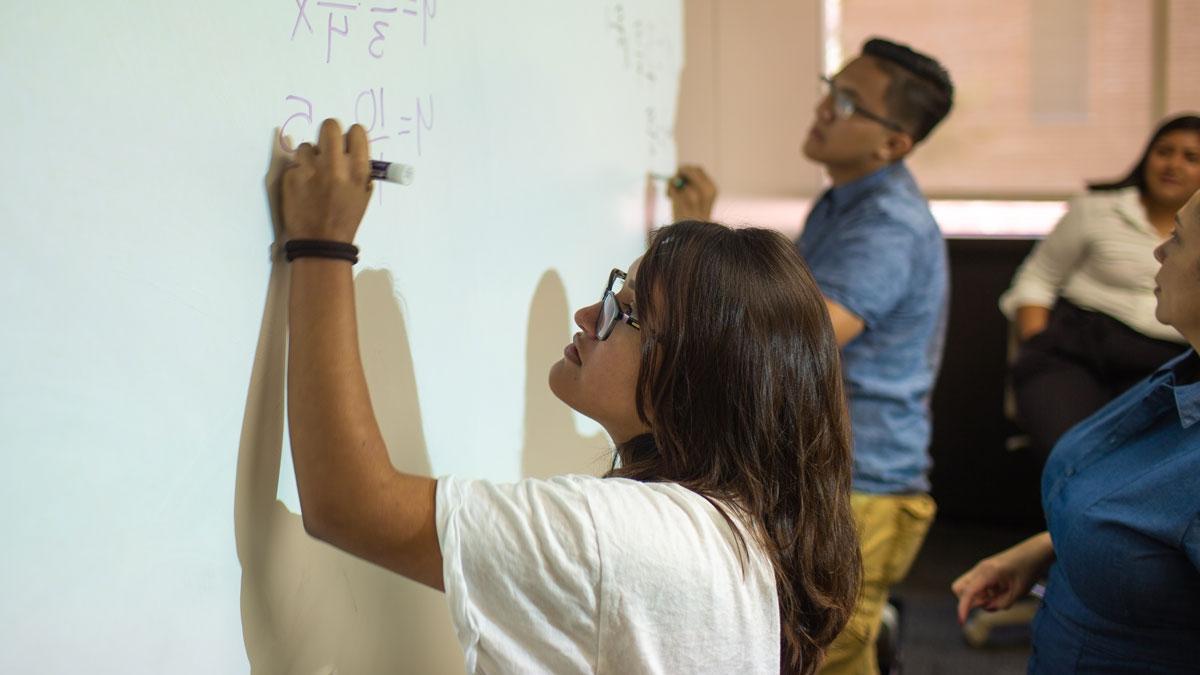 上进班学生卡拉·查韦斯和维克多·卡西利亚斯在黑板上写数学.
