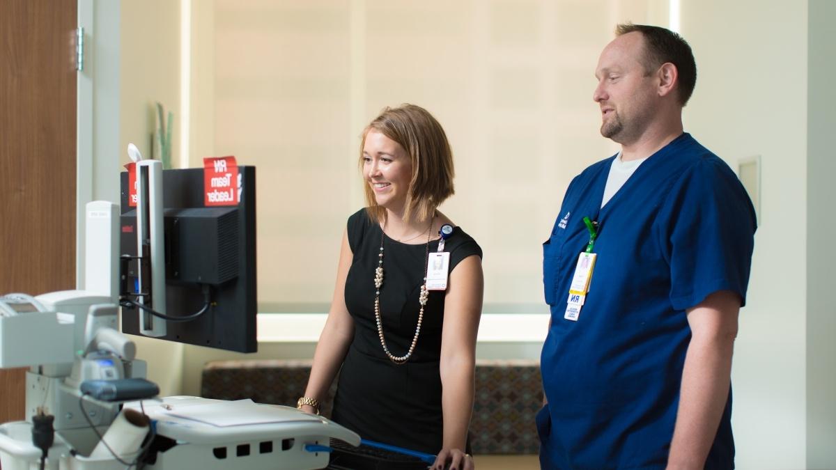 一名护士和一名医院管理人员正在查看病房内的监视器